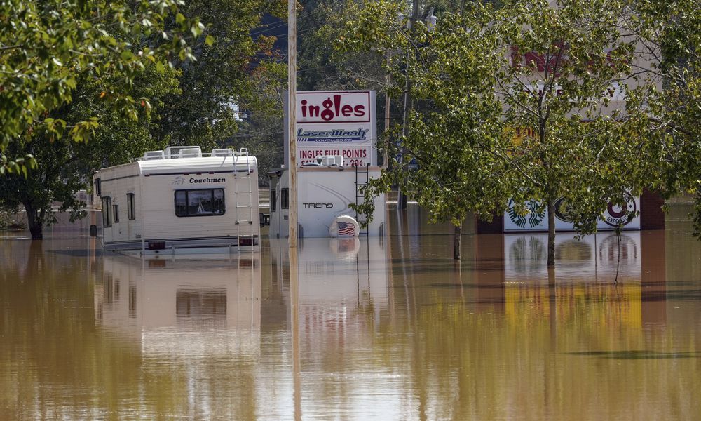 A couple of RVs are abandoned in the flooded Ingles parking lot due to the torrential rains from Hurricane Helene, Saturday, Sept. 28, 2024, in Morganton, N.C. (AP Photo/Kathy Kmonicek)