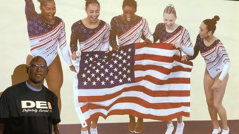 Michael Carter, the Chief Diversity Officer at Sinclair Community College and once the head basketball coach at Springfield South and Trotwood Madison high schools, stands in front of a photo of the gold-medal winning U.S. women’s gymnastics team at the 2024 Olympic Games in Paris. The quintet – (left to right) Jodan Sparks, Hezly Rivera, Simone Biles, Jade Carey and Suni Lee – are the most racially-diverse team in U.S. Olympic history and were one of the examples Carter used in his presentation last week about the way sports has been at the forefront of the positive results that come from DEI (Diversity, Equity and Inclusion) Tom Archdeacon/CONTRIBUTED