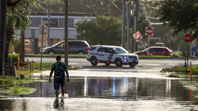 A man walks out of a street with water flooded from Hurricane Helene Friday, Sept. 27, 2024, in New Port Richey, Fla. (AP Photo/Mike Carlson)