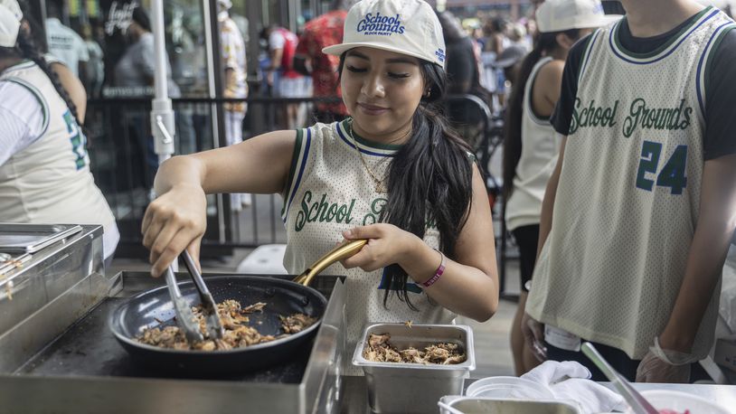 Students from Food and Finance high school make taco dough during a summer block party outside the Barclays Center, Thursday, July. 11, 2024, in New York. (AP Photo/Jeenah Moon)