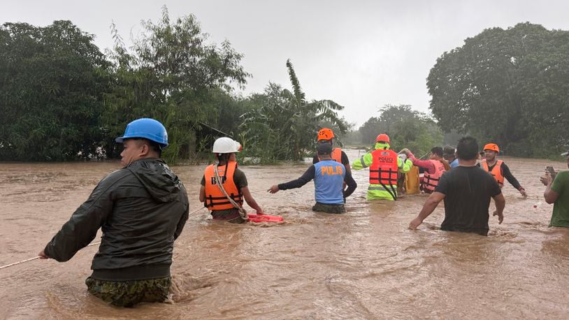 Rescuers help residents as they negotiate floods caused by powerful Typhoon Krathon locally called "Typhoon Julian" at Bacarra, Ilocos Norte province, northern Philippines on Monday, Sept. 30, 2024. (AP Photo/Bernie Dela Cruz)