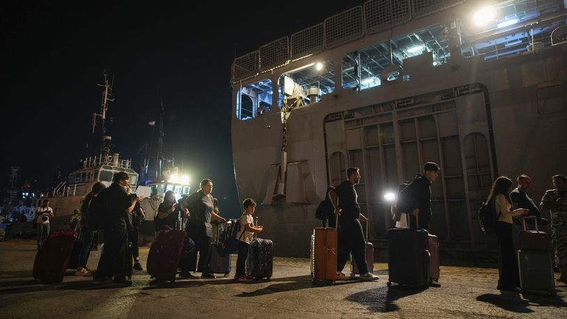 Turkish citizens walk to board Turkish military ships to evacuate them from Lebanon to Turkey, in Beirut port on Wednesday, Oct. 9, 2024. (AP Photo/Emrah Gurel)