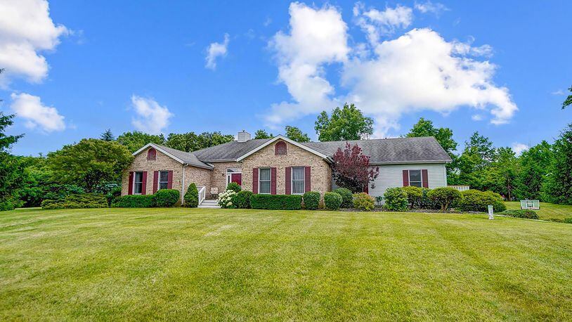 The front of the split floorplan brick and vinyl ranch has a three car attached garage and wooden front porch.