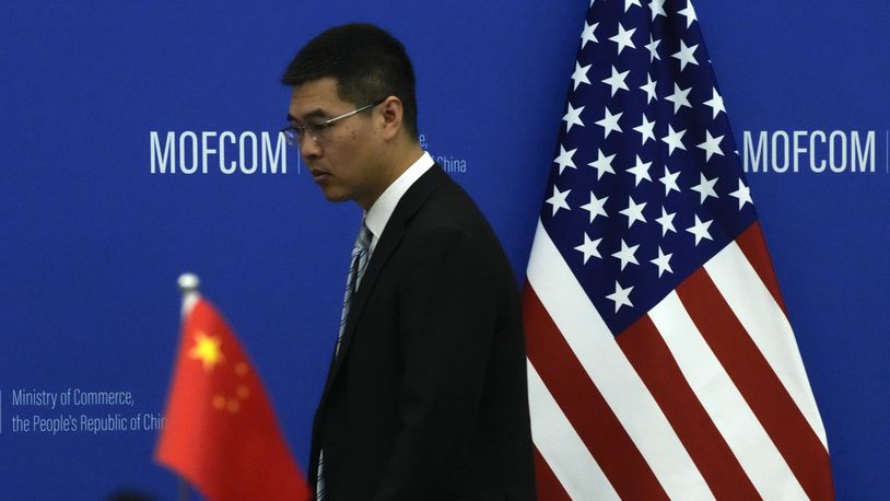 FILE - A Chinese official walks by the China and U.S. national flags before a meeting between Commerce Secretary Gina Raimondo and Chinese Minister of Commerce Wang Wentao at the Ministry of Commerce in Beijing on Aug. 28, 2023. (AP Photo/Andy Wong, Pool, File)