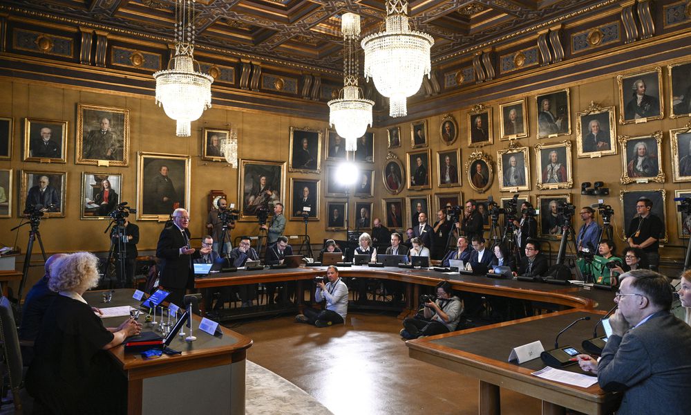 FILE - Mats Larsson, member of the Royal Academy of Sciences, standing at left, speaks during the announcement of the winner of the 2023 Nobel Prize in Physics, at the Royal Academy of Sciences, in Stockholm, on Oct. 3, 2023. (Anders Wiklund/TT News Agency via AP, File)