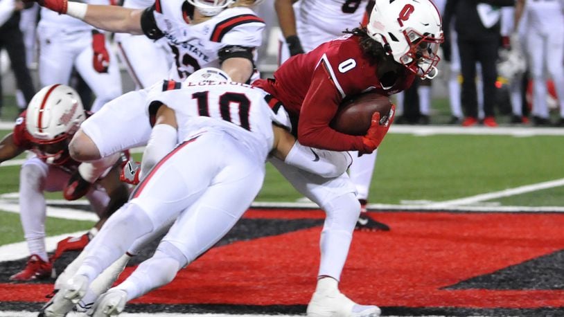 Miami's Mac Hippenhammer, 0, attempts to run out of the tackle of Ball State's Ben Egenolf, 10, during the first quarter of a Mid American Conference game on Tuesday, Nov. 22. DAVID A. MOODIE/CONTRIBUTING PHOTOGRAPHER