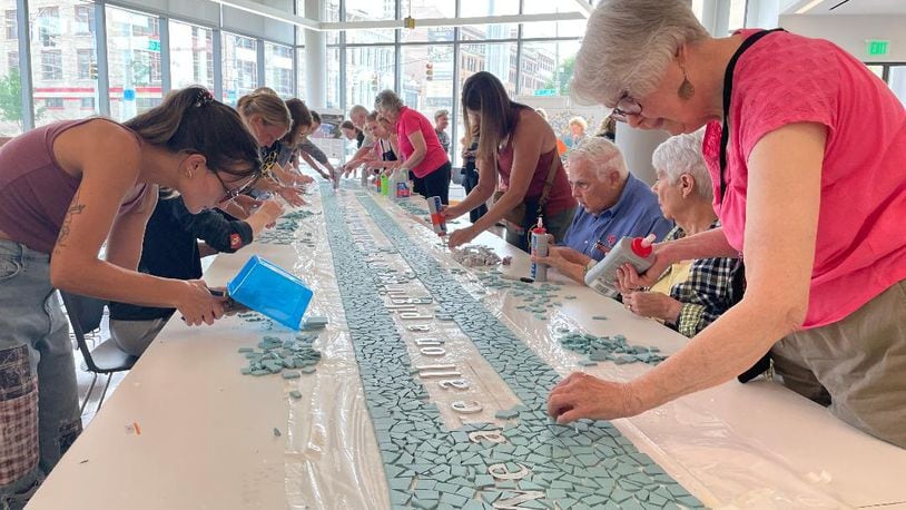 Community volunteers gathered July 11 at the Dayton Metro Library to finish the creation of the 8/4 Memorial mosaic. PHOTO BY RUSSELL FLORENCE JR.