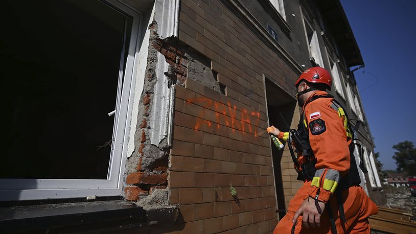 On this handout photo provided by the State Fire Service of Poland, a firefighter writes "Zakaz" (Entry prohibited), on a building damaged by following heavy flooding in the town of Stronie Slaskie, southwestern Poland, Wednesday, Sept. 18, 2024. (Tomasz Fijołek/KG PSP via AP)