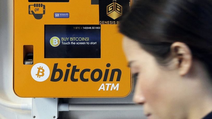 In this Dec. 21, 2017, file photo, a woman walks past the Bitcoin ATM in Hong Kong. (AP Photo/Kin Cheung)