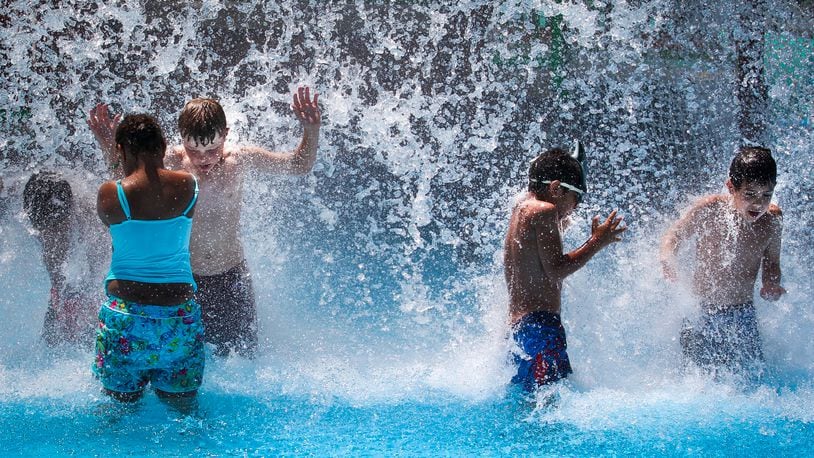 Children cool off under a waterfall at the Tipp City Family Aquatic Center. Highs will be in the low-90s, but the extreme humidity will push the heat index up. The real feel temperature is 100 degrees. JIM WITMER / STAFF
