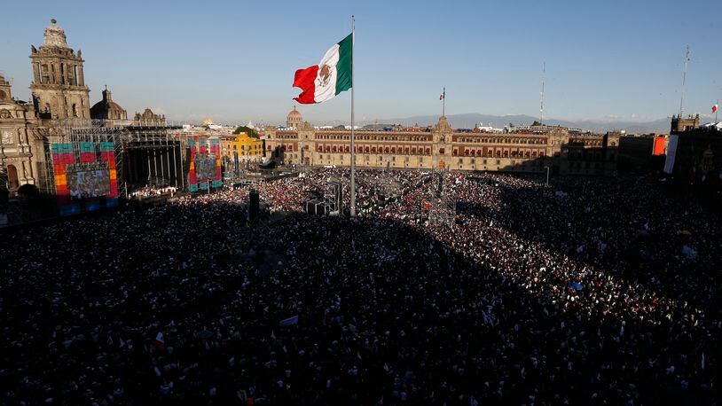 FILE - People gather in the Zocalo to celebrate Mexico's newly sworn-in president, Andres Manuel Lopez Obrador, in Mexico City, Dec. 1, 2018. Lopez Obrador swept into office with the motto laying out his administration’s priorities: “For the good of all, first the poor.” (AP Photo/Marco Ugarte, File)