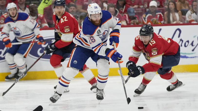 Edmonton Oilers right wing Connor Brown (28) controls the puck as Florida Panthers center Anton Lundell (15) defends during the first period of Game 5 of the NHL hockey Stanley Cup Finals, Tuesday, June 18, 2024, in Sunrise, Fla. (AP Photo/Wilfredo Lee)