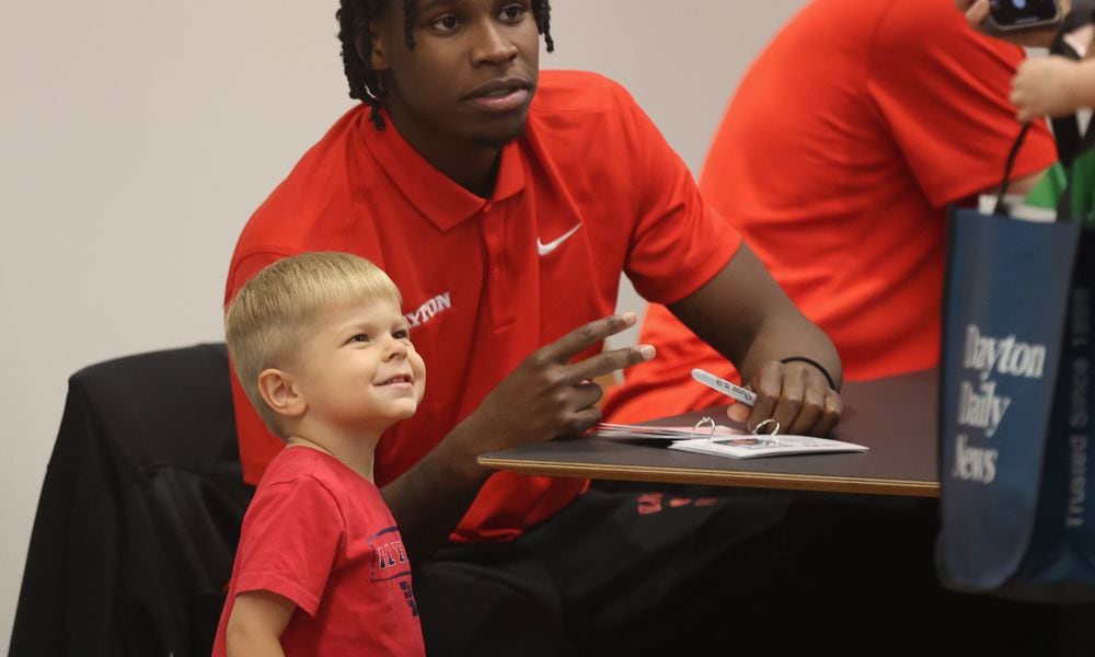 Dayton's Malachi Smith poses for a photo with a young fan, Vincent Palmer, during a meet and greet and autograph session on Wednesday, Oct. 9, 2024, at UD Arena. David Jablonski/Staff