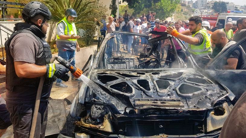 Civil Defense workers inspect the remains of a burned car that was hit by an Israeli strike in the southern port city of Sidon, Lebanon, Monday, Aug. 26, 2024. (AP Photo/Mohammed Zaatari)