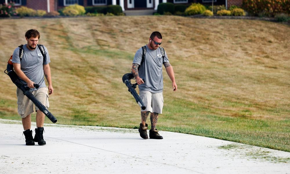 Dunham's Lawn Care employees Hayden Pond and Joshua Jackson blow grass off the driveway of a Greene County customer Wednesday, Sept. 25, 2024. The drought that has swept through Ohio and worsened over the past several weeks has turned area lawns brown and brittle. MARSHALL GORBY/STAFF