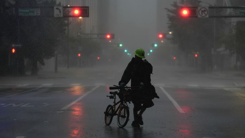 Ron Rook, who said he was looking for people in need of help or debris to clear, walks through windy and rainy conditions on a deserted street in downtown Tampa, Fla., during the approach of Hurricane Milton, Wednesday, Oct. 9, 2024. (AP Photo/Rebecca Blackwell)