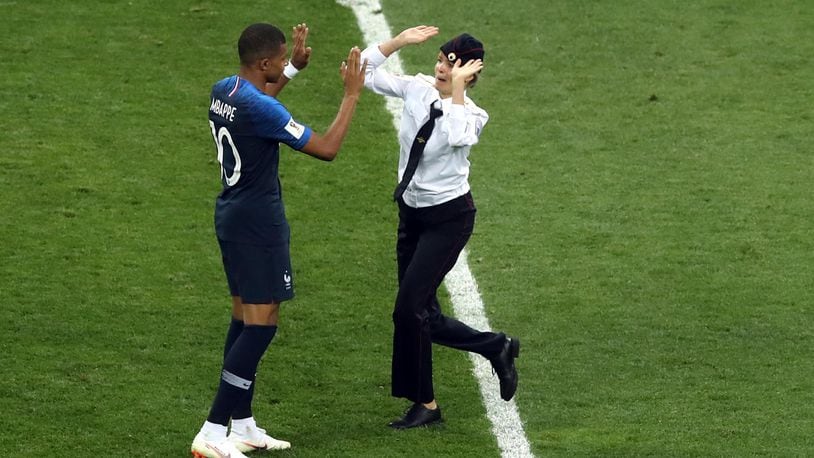 A woman who invaded the pitch approaches France's Kylian Mbappe during the final match between France and Croatia at Sunday's World Cup final.