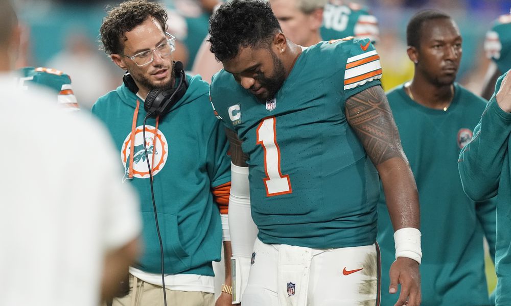 Miami Dolphins head coach Mike McDaniel talks to quarterback Tua Tagovailoa (1) as he leaves the game after suffering a concussion during the second half of an NFL football game against the Buffalo Bills, Thursday, Sept. 12, 2024, in Miami Gardens, Fla. (AP Photo/Rebecca Blackwell)