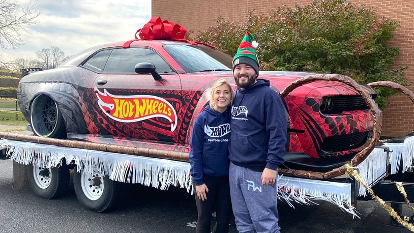 Andrew Banks (R) and his wife, Tanor, in front of a car their company, Performance Wraps, customized with a vinyl wrap.