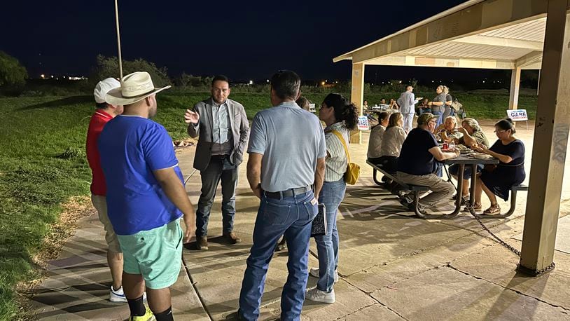 Rep. Gabe Vasquez, D-N.M., holds up a hand as he talks to guests at a "carne asada" campaign picknick, Tuesday, Aug. 20, 2024, in Chaparral, N.M., one of the region's oldest unincorporated "colonias" communities where many migrant workers settled over the past century on cheap plots of land, often with limited access to water or electricity. Vasquez touts his knowledge of the border region as the U.S.-born son of immigrants while seeking reelection in a rematch against former Republican Congresswoman Yvette Herrell. (AP Photo/Morgan Lee)