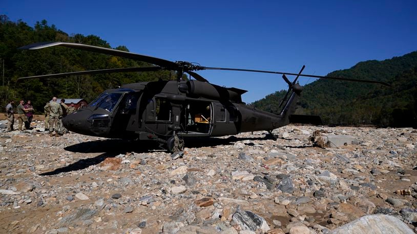 National Guard members stand outside of a Black Hawk helicopter during a supply delivery assignment on Tuesday, Oct. 8, 2024, in Burnsville, N.C. (AP Photo/Erik Verduzco)