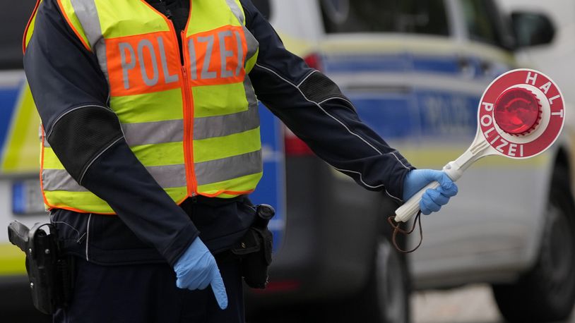 FILE - A German federal police officer stops cars and trucks at a border crossing point between Germany and Czech Republic in Furth am Wald, Germany, Tuesday, Oct. 10, 2023. (AP Photo/Matthias Schrader, File)