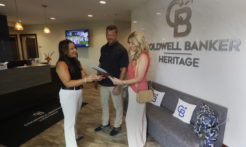 Coldwell Banker Heritage realtor, Amy Braswell talks with Matt and Brynn Coy Friday, Aug. 9, 2024 at her office in Centerville. A lawsuit settlement agreement involving the National Association of REALTORS contains two industry requirements that go into effect Saturday, affecting buyers and sellers of residential properties. MARSHALL GORBY/STAFF