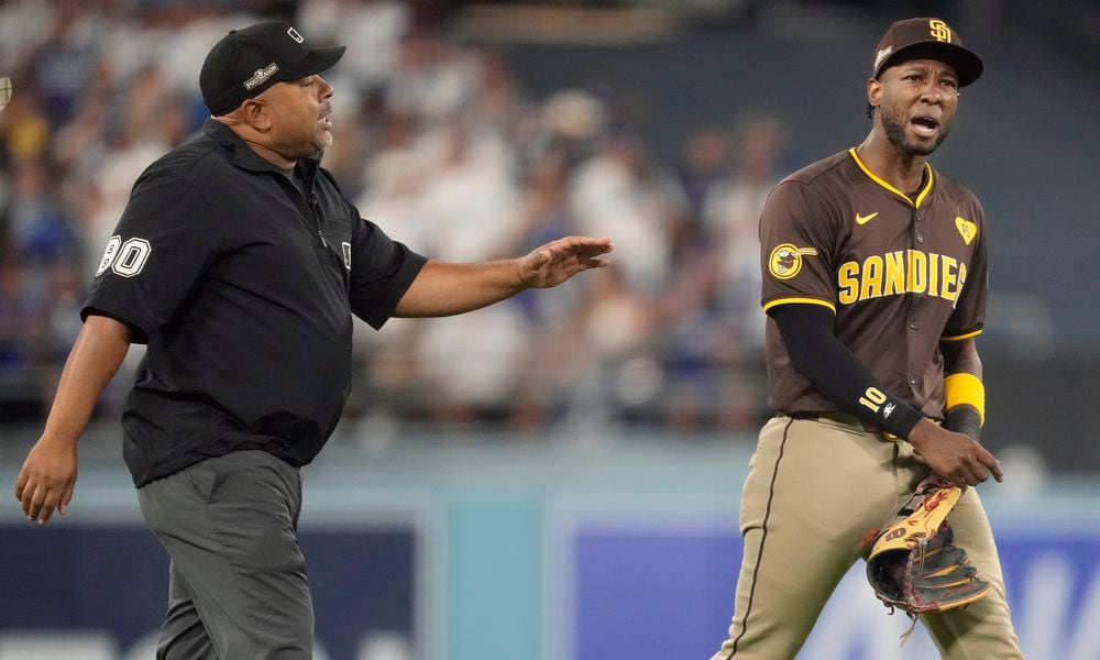 San Diego Padres left fielder Jurickson Profar, right, talks to umpire Adrian Johnson after items were thrown at Profar in the outfield during the seventh inning in Game 2 of a baseball NL Division Series against the Los Angeles Dodgers, Sunday, Oct. 6, 2024, in Los Angeles. (AP Photo/Ashley Landis)