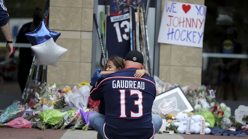 Shiloh Rivera, facing, mourns with Hylas Stemen of Columbus, at the makeshift memorial set up by fans for Blue Jackets hockey player Johnny Gaudreau in Columbus, Ohio, Aug. 30, 2024. Gaudreau, along with his brother Matthew, was fatally struck by a motorist while riding his bicycle on Thursday. (AP Photo/Joe Maiorana)