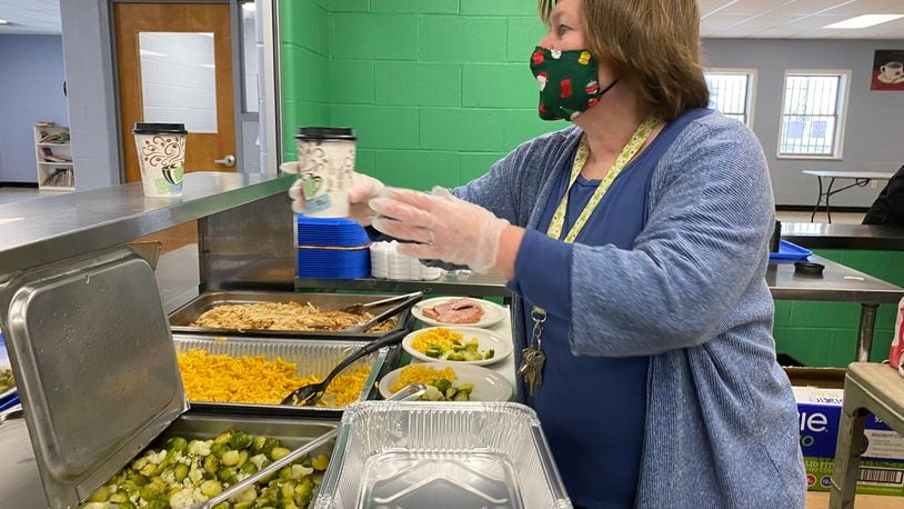 House of Bread Executive Director Melodie Bennett helps prepare a meal Friday, Dec. 25, 2020. Approximately 300 people a day get lunch from the Dayton  organization, which has founded in 1983 and has provided a lunch to the area's homeless and hungry 365 days a year since 2010. ERIC SCHWARTZBERG/STAFF