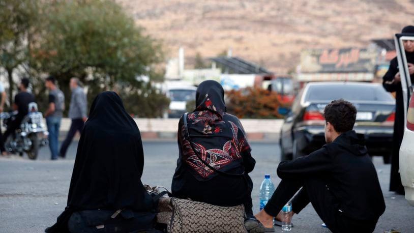 Lebanese fleeing the Israeli bombardment, sit on the ground after crossing into Syria at the Syrian-Lebanese border crossing in Jdaidet Yabous, Syria, Tuesday, Sept. 24, 2024. (AP Photo/Omar Sanadiki)