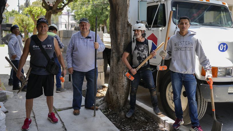 Arturo Hernandez, second from right, poses next to members of The Tree Army, a group that works to improve the urban forest, after breaking concrete placed on the roots of a tree in Mexico City, Monday, Aug. 26, 2024. (AP Photo/Eduardo Verdugo)