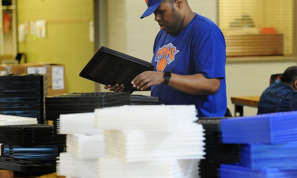 Jorge sorts through plastic trays for shipping, one of his tasks to earn a paycheck through the federal 14 c program. MARSHALL GORBY\STAFF