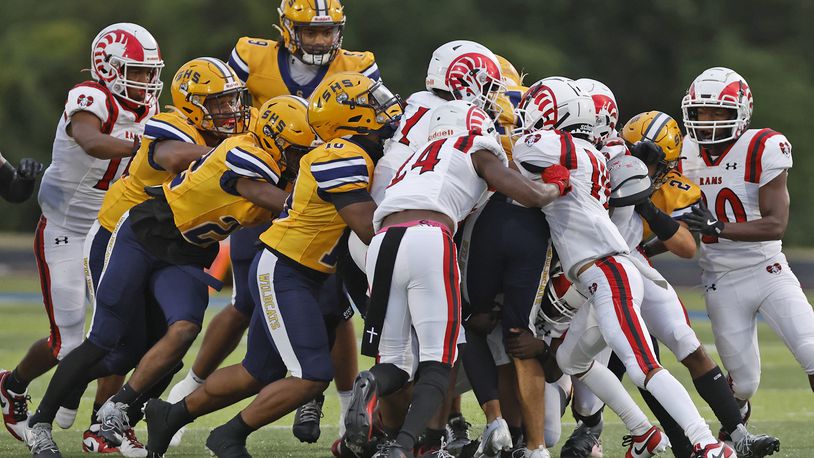 The Springfield football team pushes their teammate Jamil Miller and the Trotwood defense for extra yards as Miller carries the ball. BILL LACKEY/STAFF