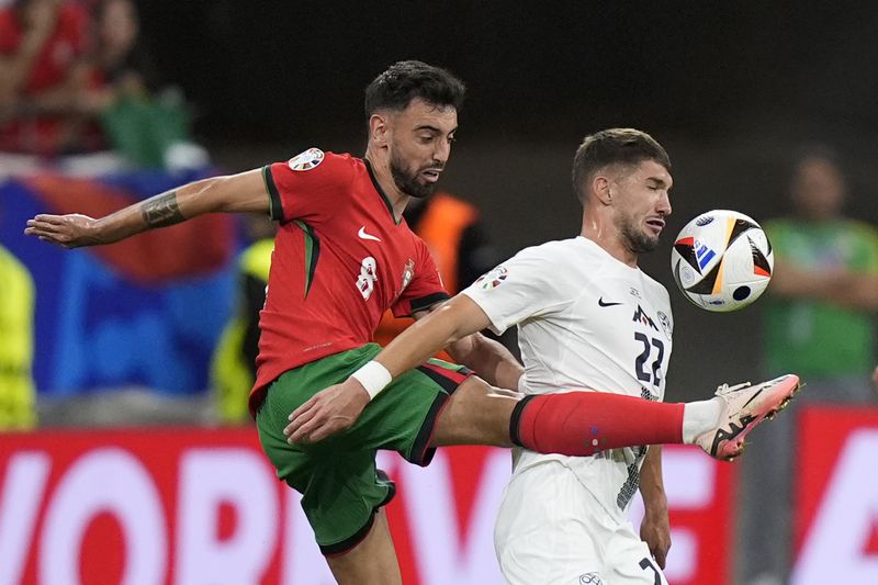 Portugal's Bruno Fernandes, left, and Slovenia's Adam Gnezda Cerin fight for the ball during a round of sixteen match between Portugal and Slovenia at the Euro 2024 soccer tournament in Frankfurt, Germany, Monday, July 1, 2024. (AP Photo/Matthias Schrader)