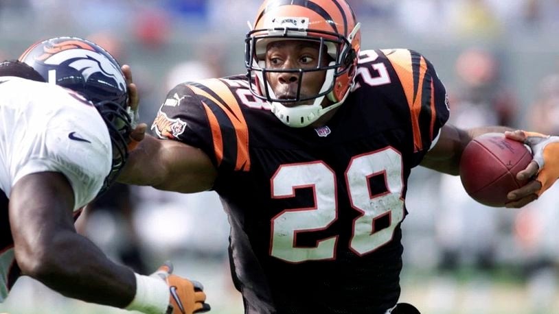 FILE - Cincinnati Bengals running back Corey Dillon (28) pushes away Denver Broncos defender Al Wilson, left, in the first half Sunday, Oct. 22, 2000, in Cincinnati. The Cincinnati Bengals are adding running back Corey Dillon and nose tackle Tim Krumrie to the team's Ring of Honor this fall. (AP Photo/Al Behrman, File)