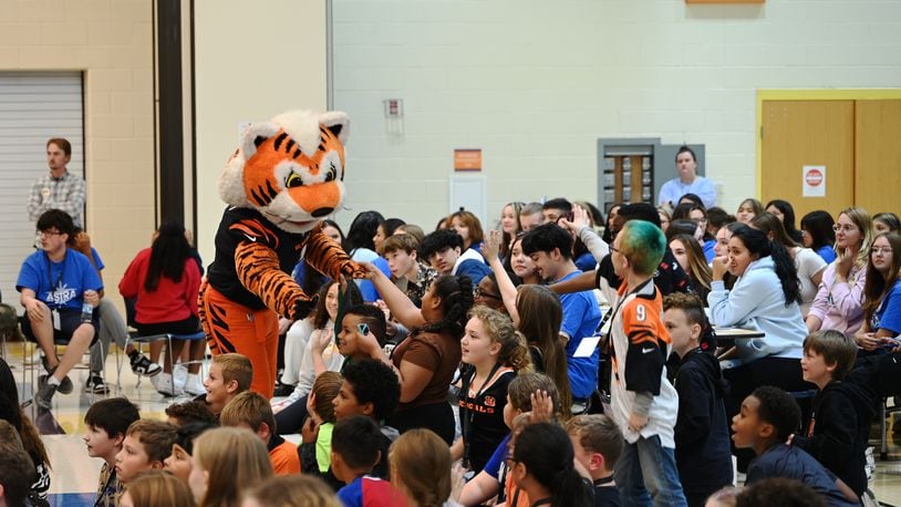 Just a Pair of Shoes, a nonprofit organization that distributes free high-end shoes distributed 120 pairs to students at Highland Elementary School in the Hamilton City School District. The event was sponsored by Kettering Health and the Cincinnati Bengals. After receiving the shoes, the students put them on and tried them out. Pictured is Bengals mascot Who Dey greeting Highland Elementary students before they received a free pair of shoes and three pairs of Bombas socks.  MICHAEL D. PITMAN/STAFF