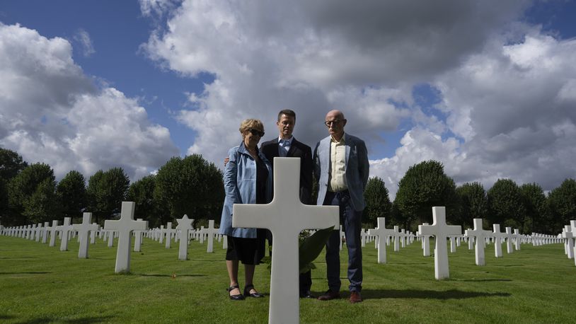 Eighty years after the liberation of the south of the Netherlands, Scott Taylor, center, Ton Hermes and Maria Kleijnen stand next to the grave of Scott's grandfather Second Lt. Royce Taylor, a bombardier with the 527 Bomb Squadron, at the Netherlands American Cemetery in Margraten, southern Netherlands, on Wednesday, Sept. 11, 2024. (AP Photo/Peter Dejong)