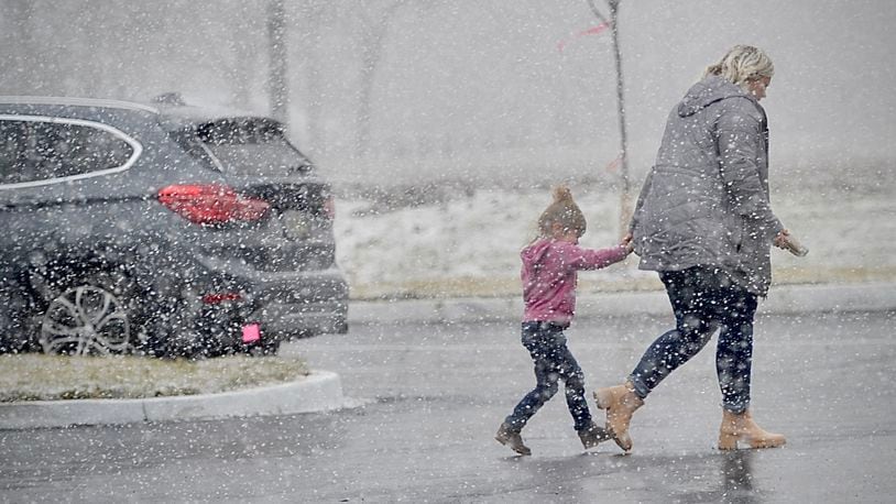 The first snowfall of the season as people scrambling Monday, Dec. 18, 2023 like these two on E. Main St. in New Lebanon at the Dollar General. MARSHALL GORBY \STAFF