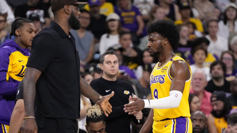 Los Angeles Lakers' LeBron James, left, greets his son, Bronny James as Bronny comes off the court during the first half of a preseason NBA basketball game, Friday, Oct. 4, 2024, in Palm Desert, Calif. (AP Photo/Mark J. Terrill)