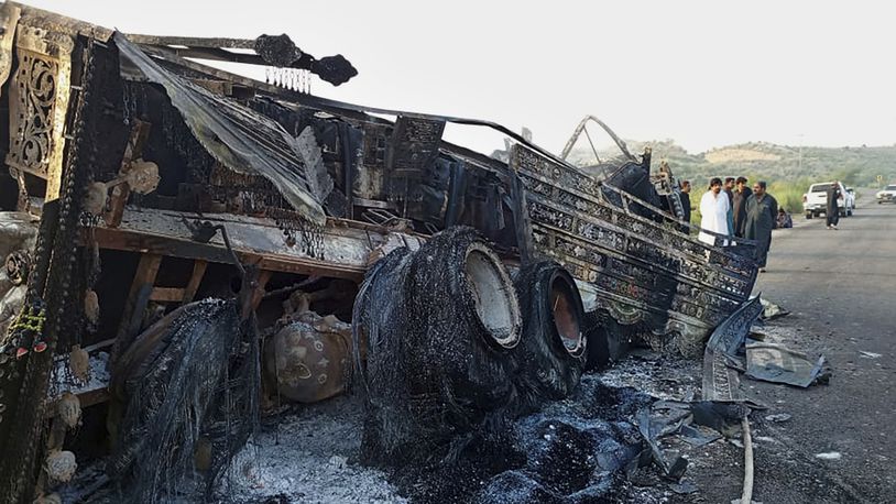 People look at a burnt vehicle which was torched by gunmen after they killed passengers at a highway in Musakhail, a district in Baluchistan province in restive southwestern Pakistan, Monday, Aug. 26, 2024. (AP Photo/Rahmat Khan)