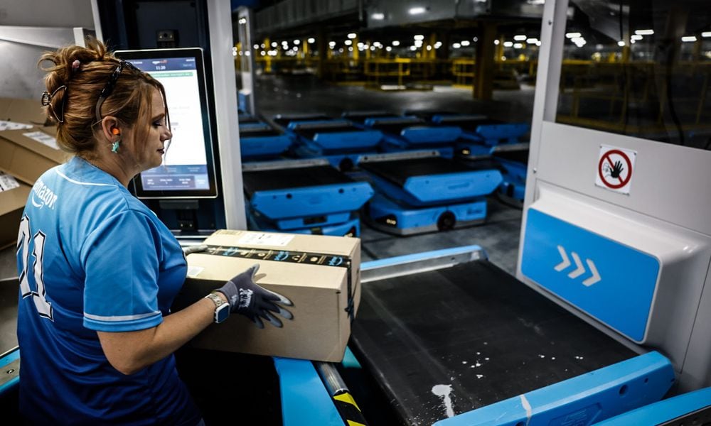 Amy Stuckey loads boxes onto robots that whisk products around Amazon's 2.8 million square feet Amazon Union Fulfillment Center. JIM NOELKER/STAFF