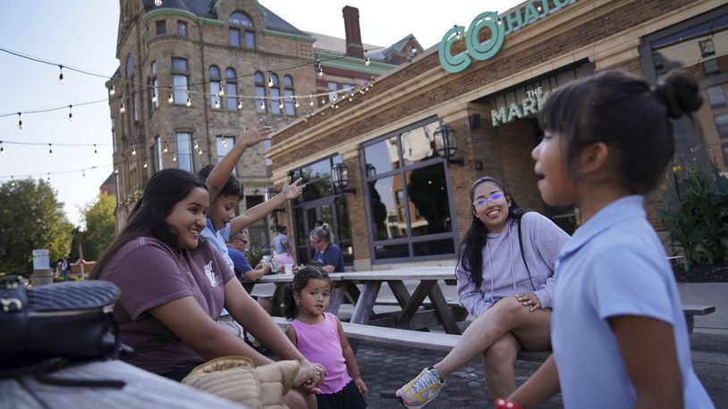 Alondra Nunez, left, and her sister Monserrat, second from right, sit with family members outside of The Market, where their brother owns the restaurant Chido's Tacos, Monday, Sept. 16, 2024, in Springfield, Ohio. (AP Photo/Jessie Wardarski)