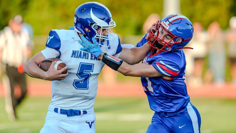 Cutline 1: Miami East High School sophomore quarterback KJ Gustin stiff arms Northwestern junior Tyler Romine during their game on Thursday night at Taylor Field in Springfield. The Vikings won 21-20. Michael Cooper/CONTRIBUTED