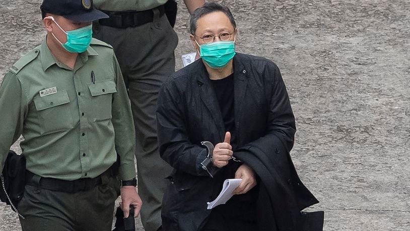 FILE - Former law professor Benny Tai, a key figure in Hong Kong's 2014 Occupy Central protests and also was one of the main organizers of the primaries, who was arrested under Hong Kong's national security law, gives the thumbs up as he is escorted by Correctional Services officers in Hong Kong March 2, 2021. A Hong Kong court began mitigation hearings for prominent pro-democracy activists who were convicted under a national security law and now face up to life in prison.(AP Photo/Kin Cheung, File)