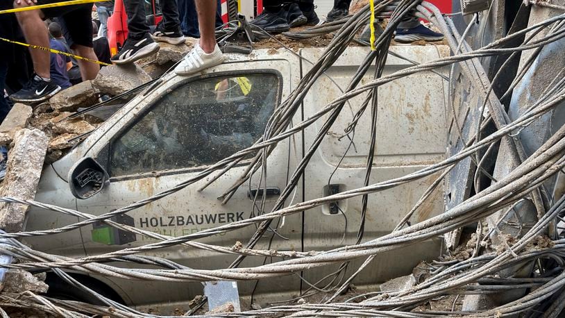 People stand on top of a damaged car at the scene of a missile strike in the southern suburbs of Beirut, Friday, Sept. 20, 2024. (AP Photo/Bilal Hussein)