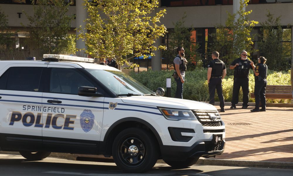 Springfield and Dayton police officers outside the City Hall building following an evacuation due to a threat Thursday. BILL LACKEY/STAFF