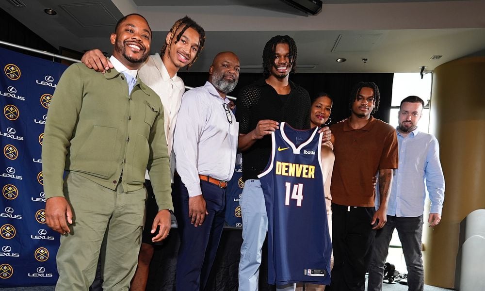 Denver Nuggets 2024 first-round draft pick DaRon Holmes II, center, holds up his jersey for a photograph with, from left, business manager Mitch Brown, brother Cameron Holmes, father DaRon, Sr., mother Tomika, brother Quintyn and agent Aaron Reilly during an NBA basketball news conference Monday, July 1, 2024, in Denver. (AP Photo/David Zalubowski)