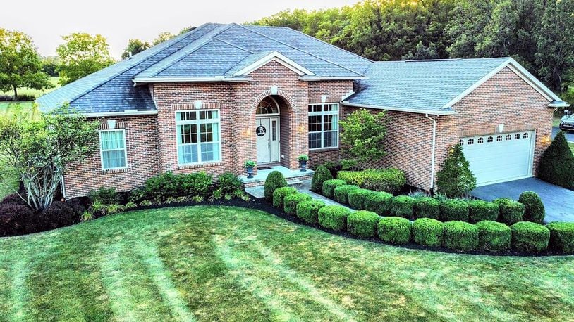 The front of the brick ranch home has a two car attached garage with openers and a covered entry. It has been recently landscaped.