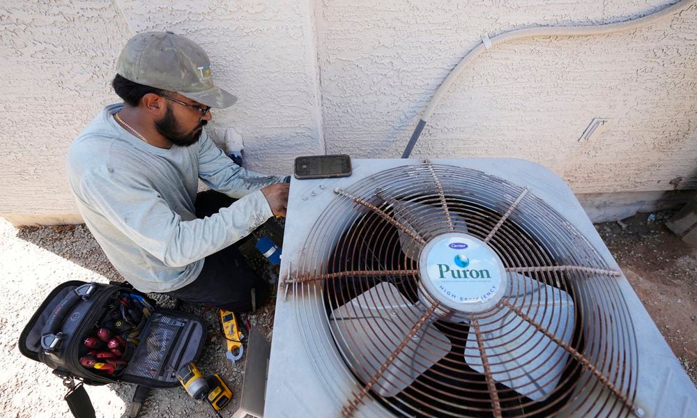 Total Refrigeration service tech Michael Villa works on replacing a fan motor on an air conditioning unit as temperatures are expected to hit 117-degrees Wednesday, July 19, 2023, in Phoenix. Most of the Maricopa County's 645 heat-related deaths last year were outdoors, but 156 people died in their homes. (AP Photo/Ross D. Franklin)